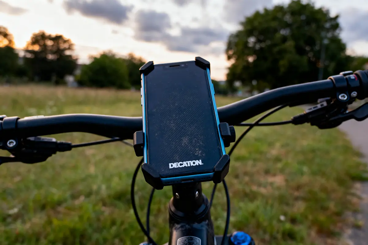 Guidon de vélo avec téléphone fixé sur support, champ en arrière-plan.