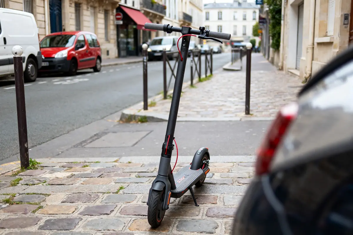 Trottinette électrique Urban Glide 100 Shark Lite sur trottoir pavé en ville